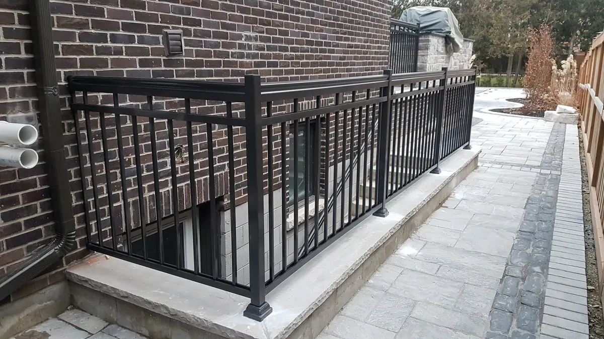 Extended black aluminum railing along raised concrete walkway and deck
