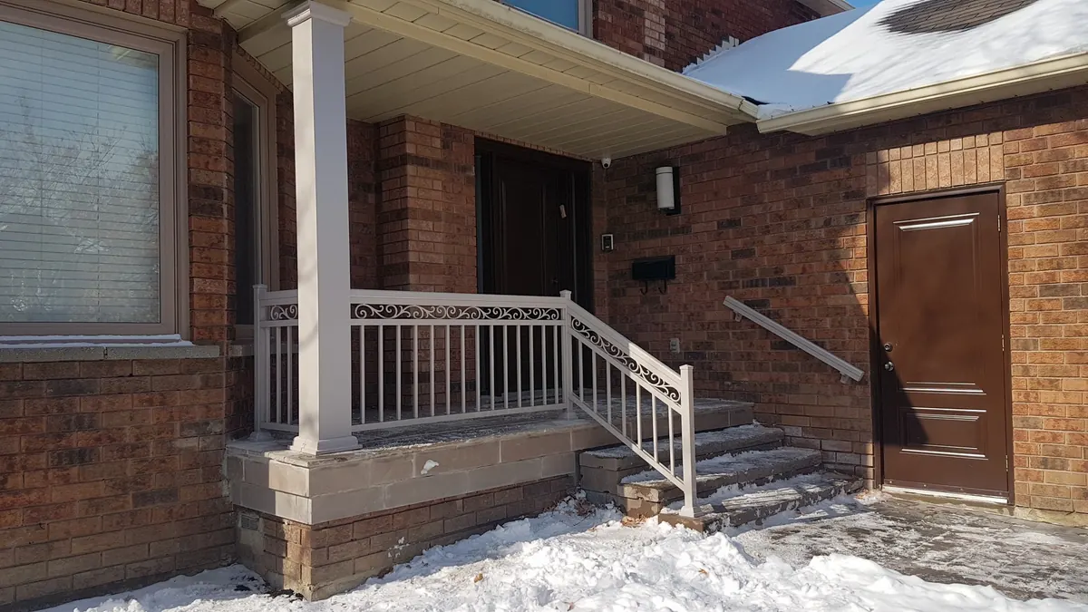 Decorative aluminum porch railing with belly-cast scrollwork on stone columns