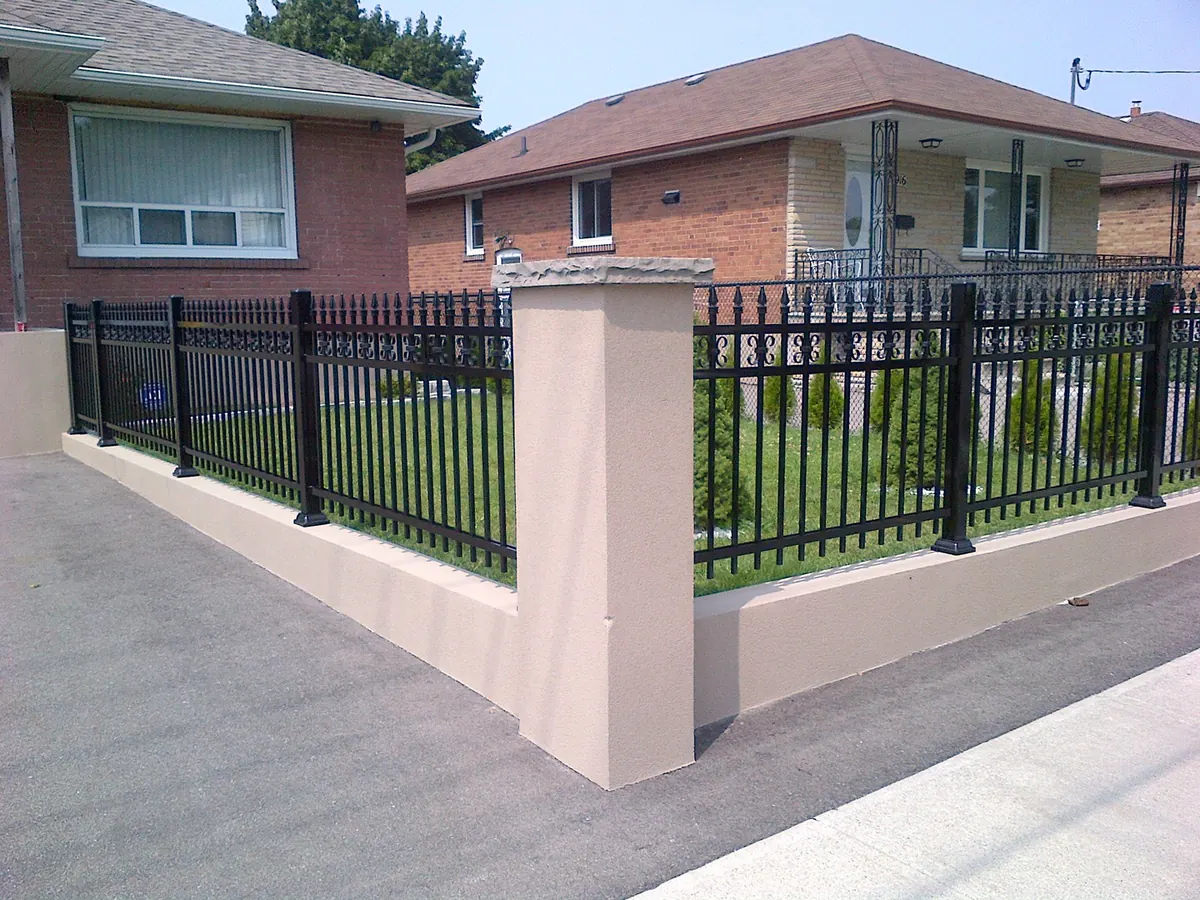 Black aluminum spear-top fence on streetside property with stucco column post