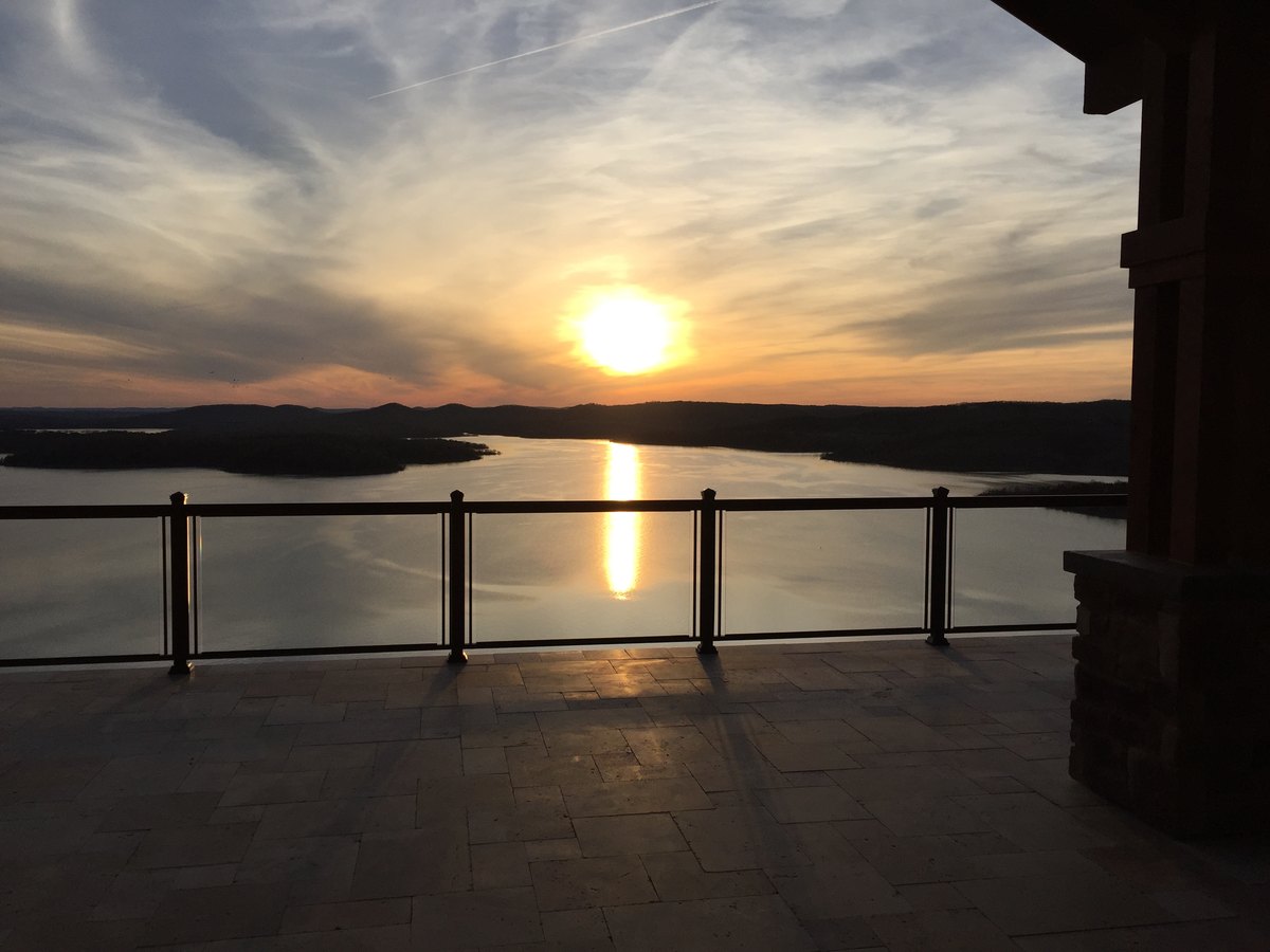Frameless glass railing on a deck overlooking a lake at sunset