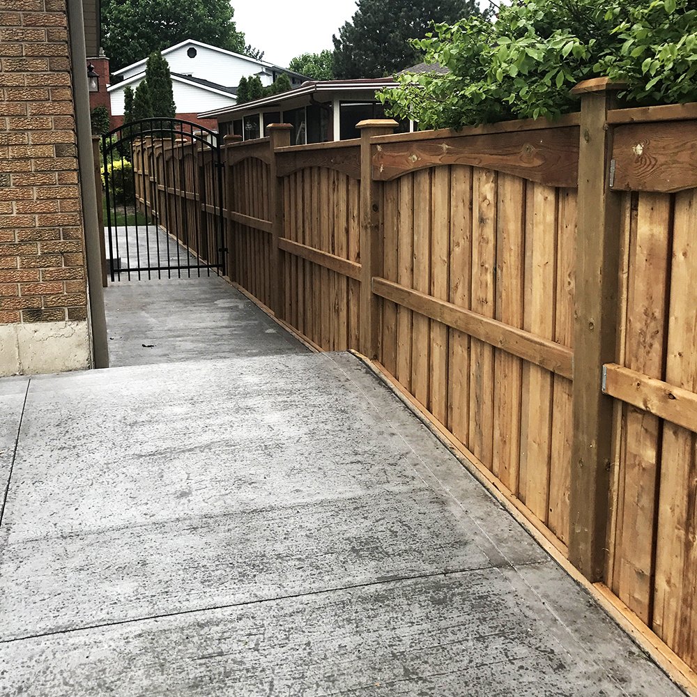 Stained wood privacy fence with black aluminum gate at driveway